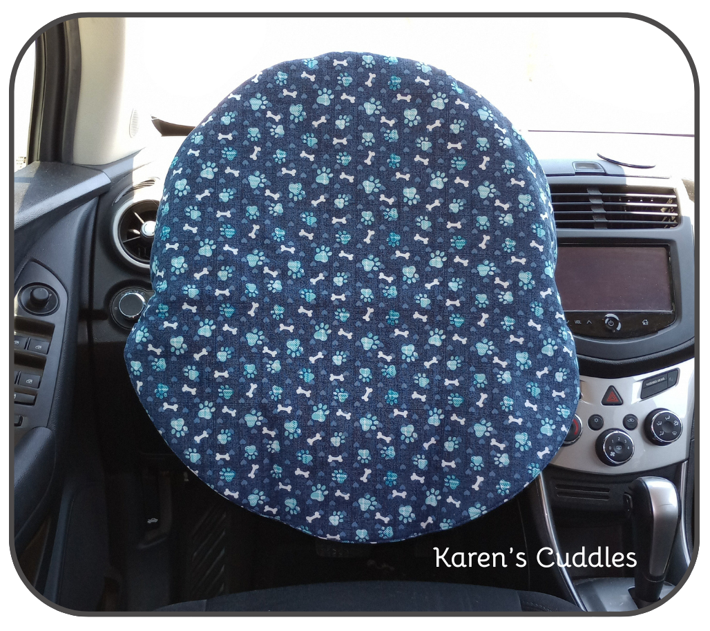 blue paw prints and white dog bones on a dark blue fabric covering a steering wheel