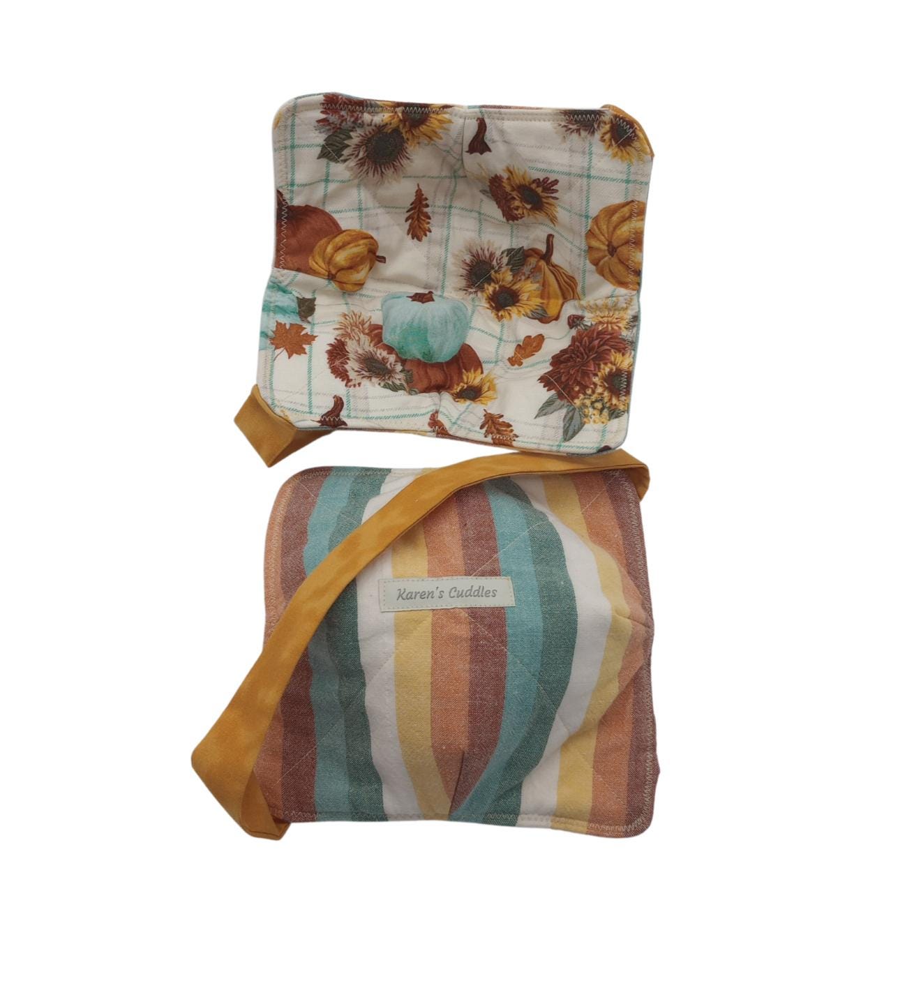 This bowl festive cozy is reversible, features a cream cotton fabric with subtle light blue squares, pumpkins and leaves on one side and stripes of fall colors on the reverse side.  Bowl cozies are hot pads designed to hold hot or cold bowls, has a versatile strap for hand support and easy storage. They can be used in the microwave to reheat food as well as double for a placemat. This cozy offers two sizes holding a small soup bowl up to 6.5&quot; diameter or a medium pasta bowl up to 7.5” diameter.