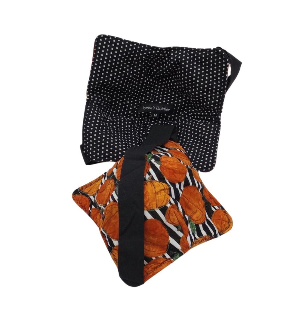This bowl cozy is reversible, features black cotton fabric with white polka dots on one side and black-white stripes with pumpkins on the reverse side.  Bowl cozies are hot pads designed to hold hot or cold bowls, has a black versatile strap for hand support and easy storage. They can be used in the microwave to reheat food as well as double for a placemat. This cozy offers two sizes holding a small soup bowl up to 6.5&quot; diameter or a medium pasta bowl up to 7.5” diameter.