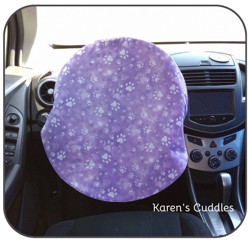 paws on purple fabric covering steering wheel