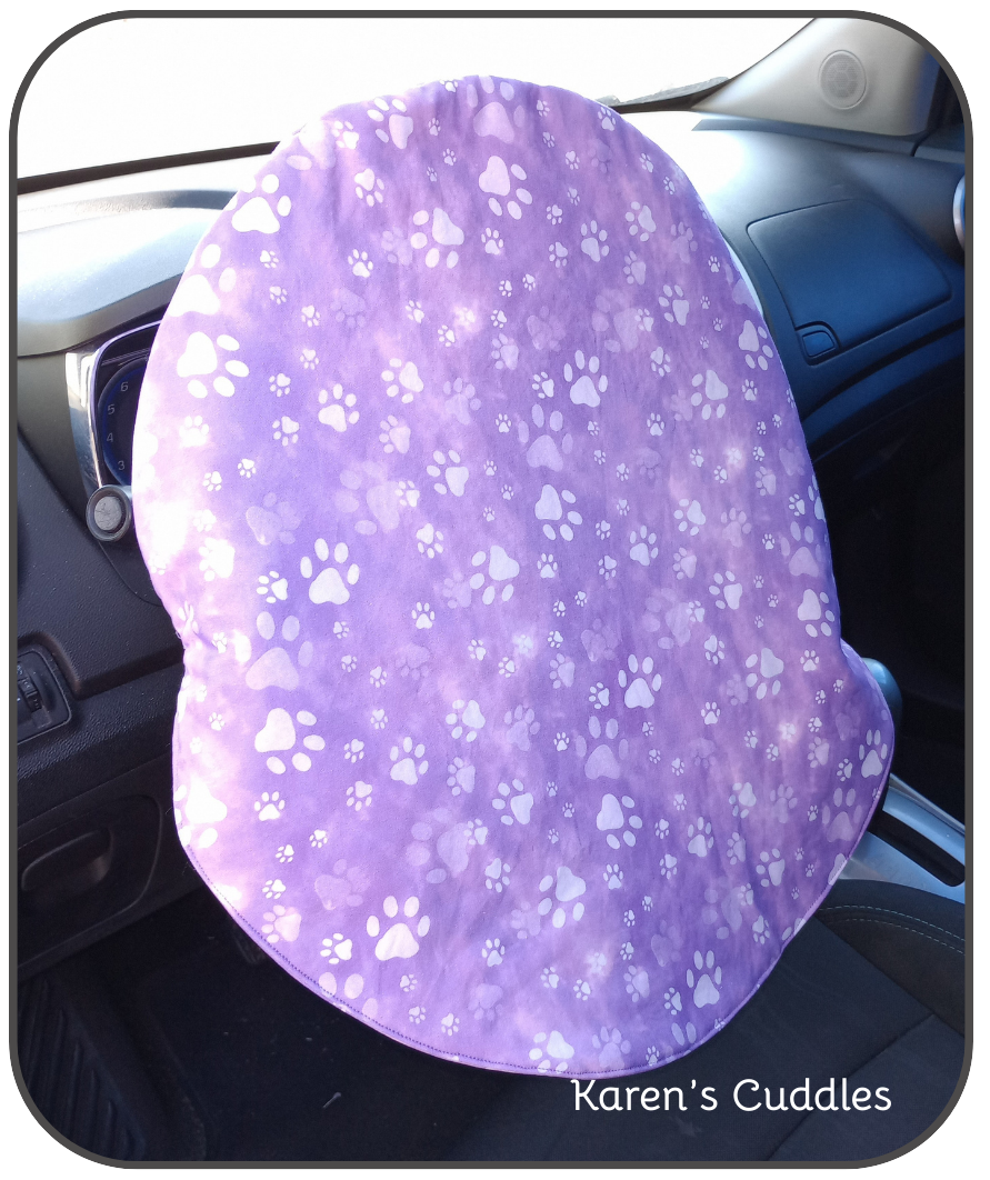 paw prints on purple fabric on car steering wheel
