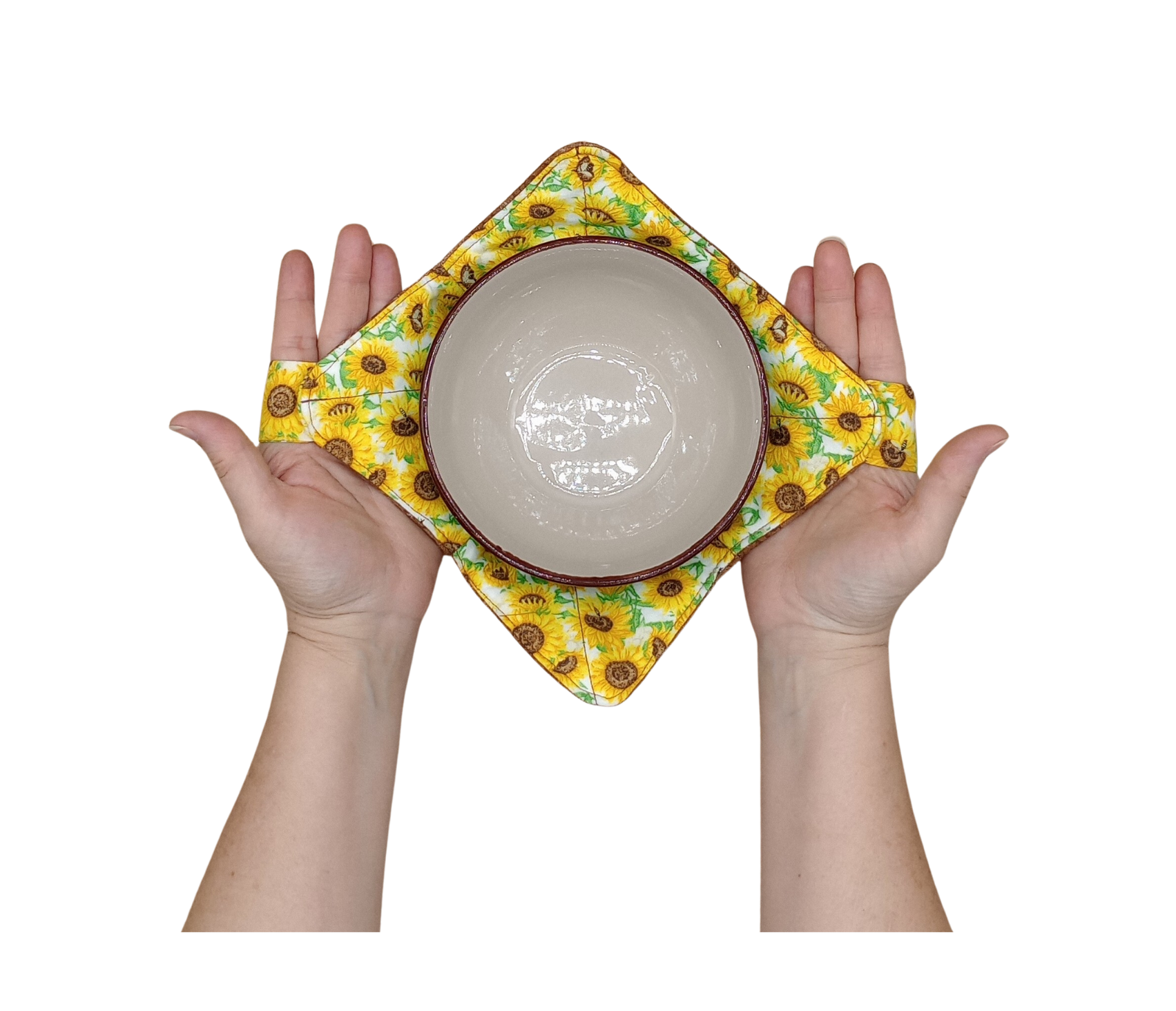 Hands holding a bowl with a sunflower-patterned bowl hot pad on a white background